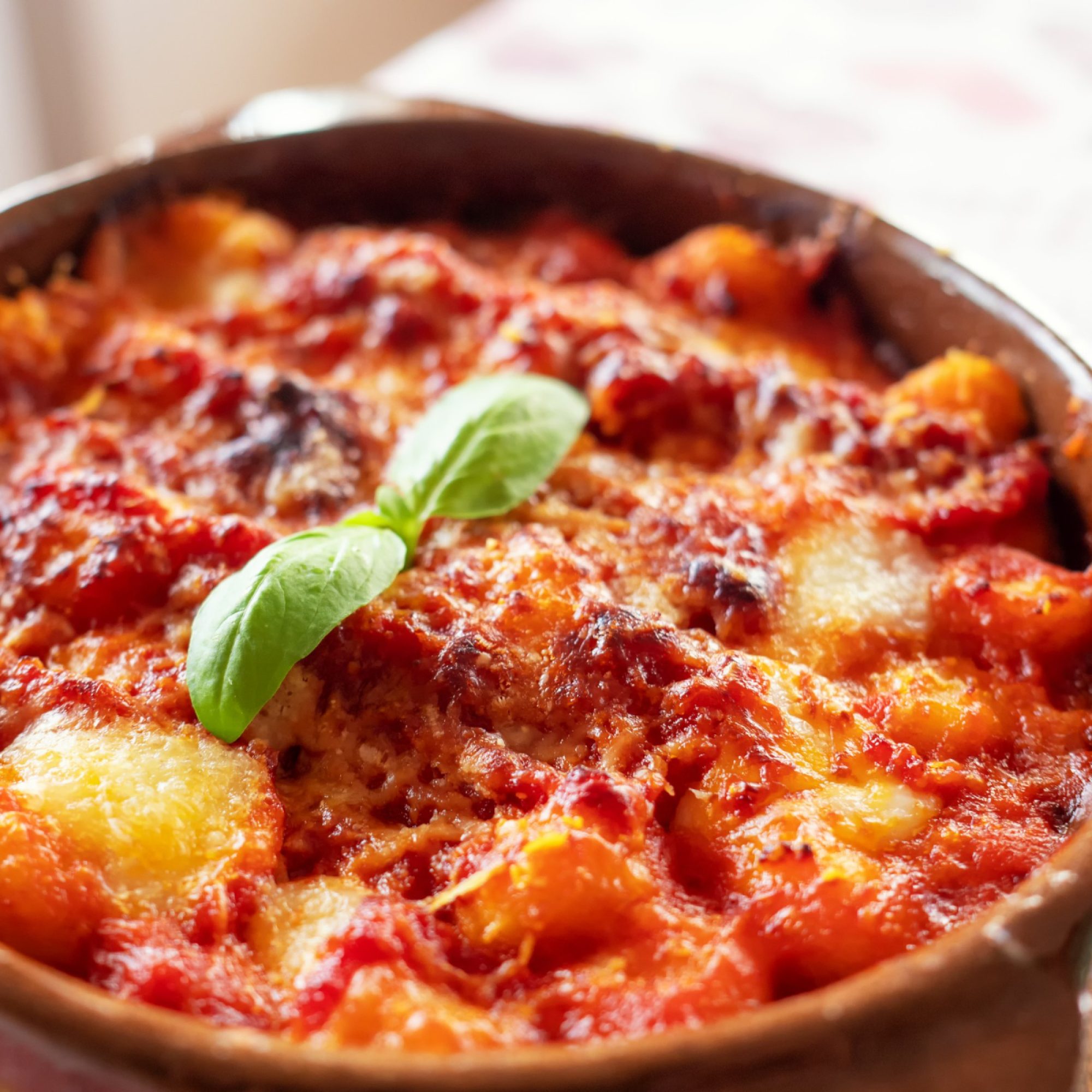 gnocchi-alla-sorrentina-gnocchi-di-patate-italiane-in-salsa-di-pomodoro-gratinati-con-mozzarella-in-un-piatto-di-terracotta-messa-a-fuoco-selettiva